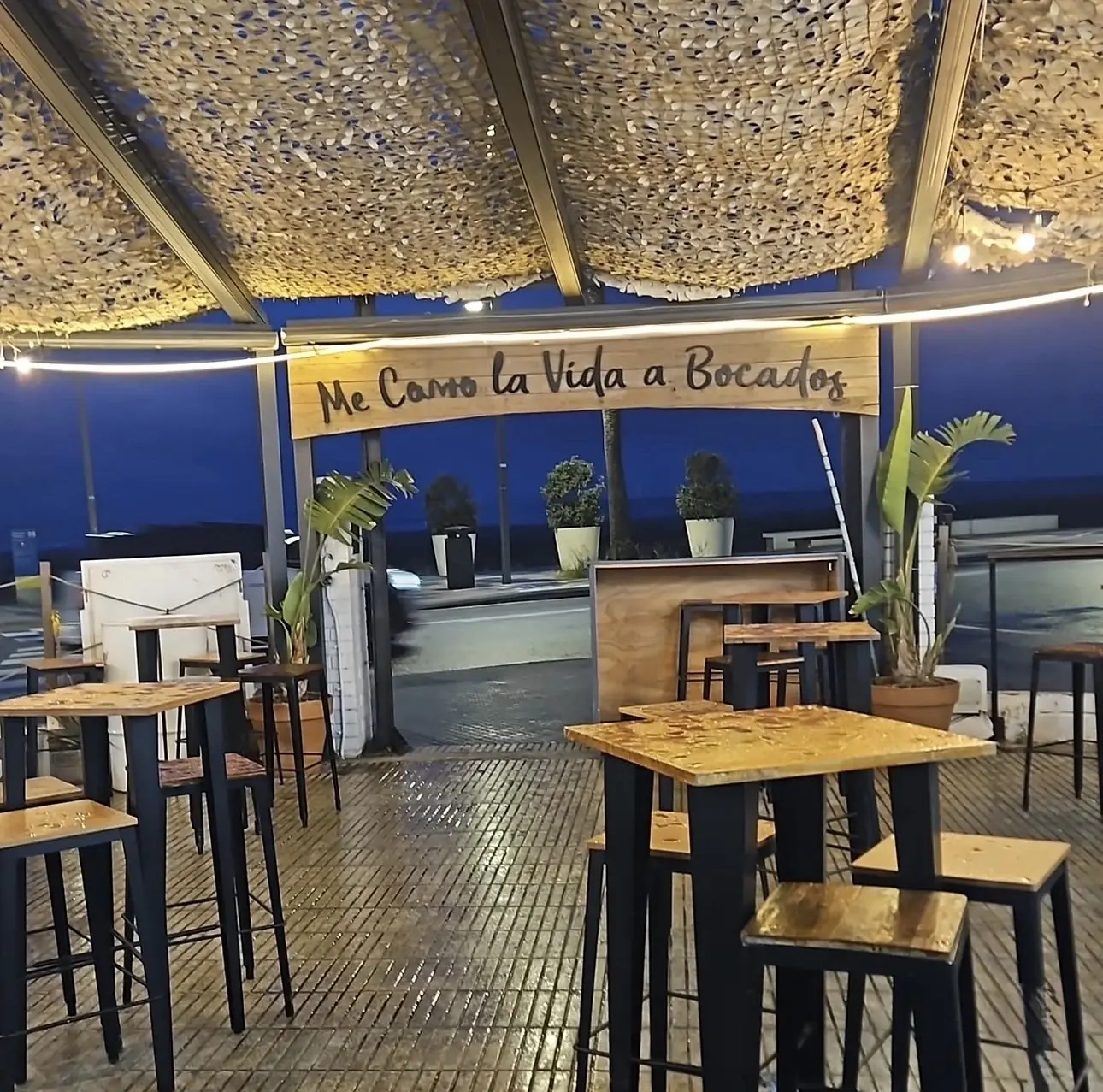 Terraza de Bocados de noche con el rótulo Me como la vida a bocados